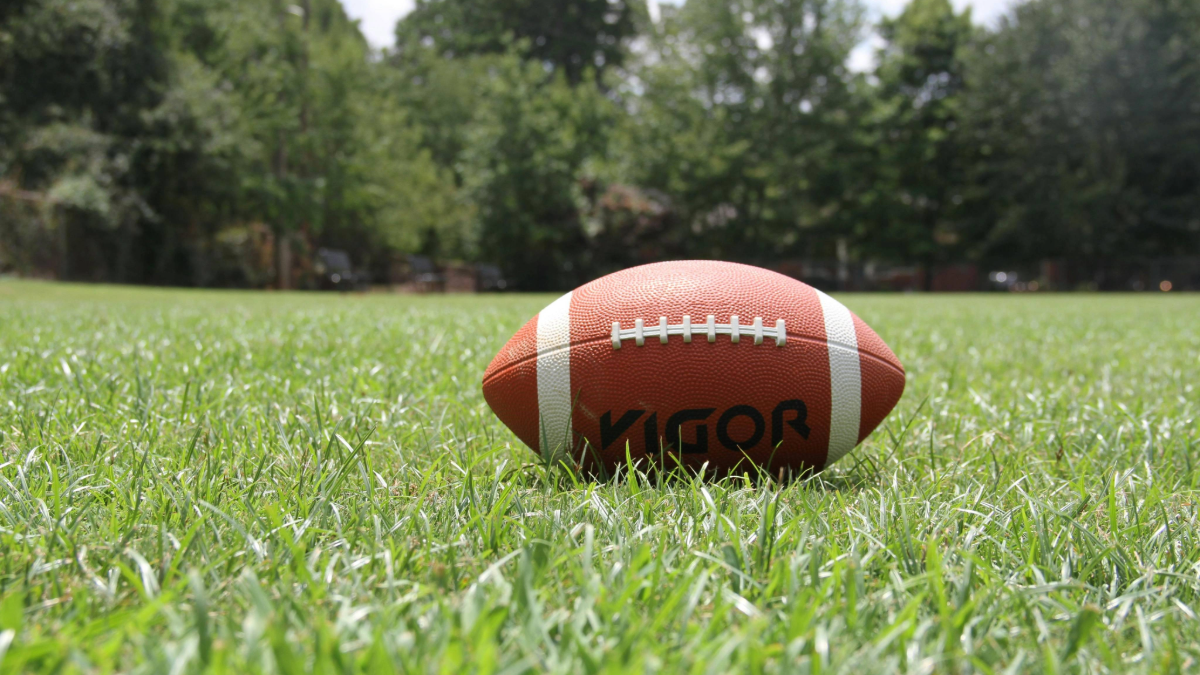 American football laying on green grass